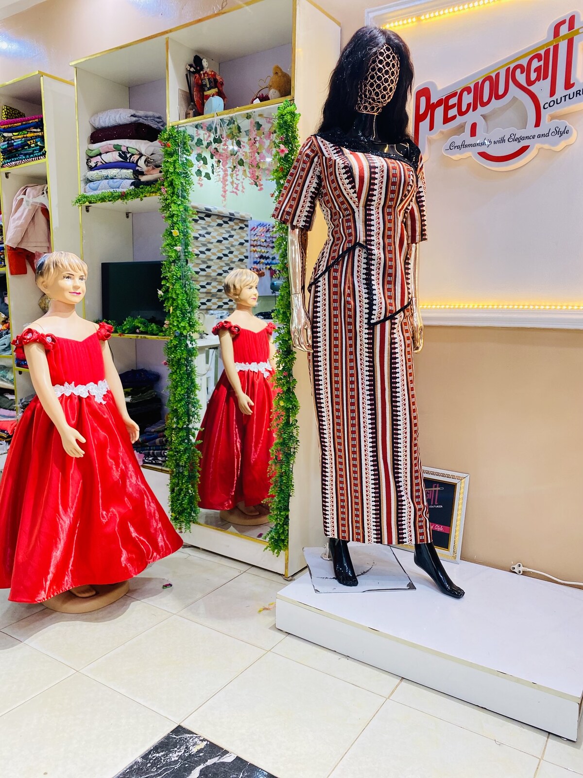 Atelier window display with red gown and aso-oke piece